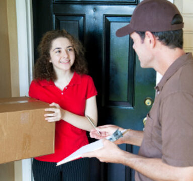Delivery man brings a package to a customer's door and waits for a signature.